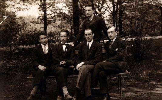 Grupa młodych mężczyzn na ławce w parku w Rydze (Łotwa), z prawej siedzi Wiktor Najmowicz, podpis na odwrocie: Towarzystwo pułkowe.