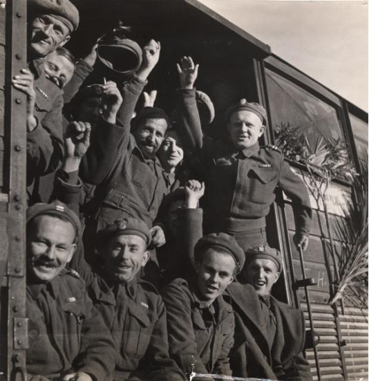 Polscy żołnierze wracający pociągiem z Włoch do kraju. Widoczne są kwiaty przytwierdzone do wagonu pociągu.