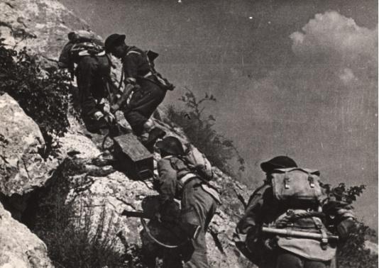 Walki 2 Korpusu Polskiego pod Monte Cassino. Wyposażeni w amunicję żołnierze wspinają się po stromym wzgórzu. Podpis na odwrocie: Zaopatrywanie w amunicję podczas walki.