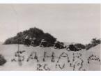 Żołnierze Samodzielnej Brygady Strzelców Karpackich odpoczywają na pustynnym piasku. Na pierwszym planie widoczny jest napis utworzony z kęp trawy: Sahara oraz data.