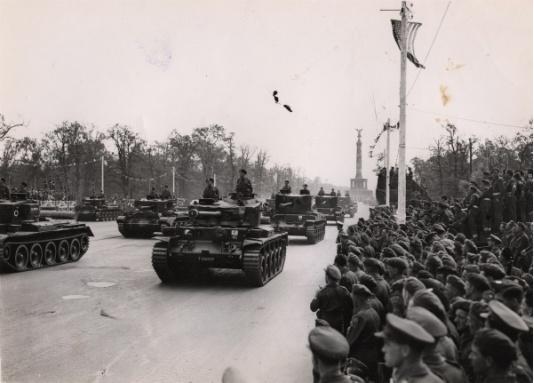 Przejazd czołgów podczas Wielkiej Zwycięskiej Defilady, w której uczestniczył Winston Churchill. Na pierwszym planie - żołnierze obserwujący defiladę, w oddali widoczna jest Siegessaule - pruska kolumna zwycięstwa. 